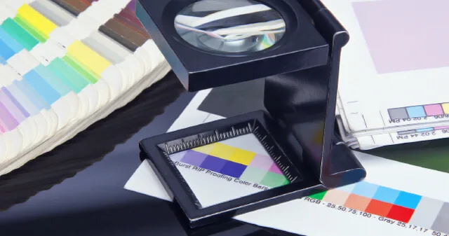 Colour swatches and a printed proof under a loupe